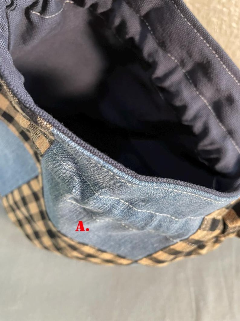 May include: Close-up of a patchwork bag with denim, blue, and tan gingham fabric. The bag's interior is a solid dark blue. The letter "A" is visible on the bag.