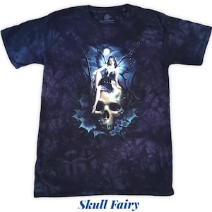 May include: A dark blue tie-dye t-shirt with a graphic print of a fairy sitting on a skull with blue wings and flowers. The text "Skull Fairy" is printed below the image.