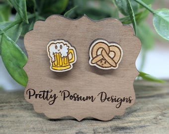 May include: Wooden earrings with a beer mug and pretzel design. The earrings are on a wooden display card with the text "Pretty 'Possum Designs".
