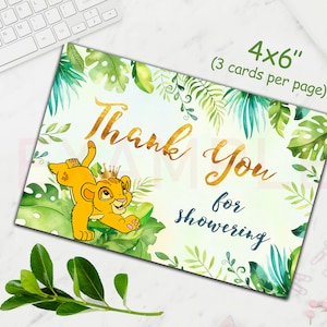 Pode incluir: Um cart&atilde;o de agradecimento para ch&aacute; de beb&ecirc; de 10 x 15 cm com um filhote de le&atilde;o de desenho animado com uma coroa de ouro, cercado por folhas tropicais verdes. As palavras "Thank You for showering" est&atilde;o em ouro e azul.