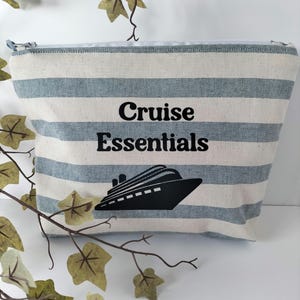 May include: A striped blue and white canvas zippered pouch with the text "Cruise Essentials" and a black silhouette of a cruise ship.