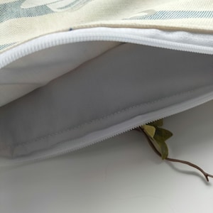 May include: A white zippered pouch with a blue and white striped fabric exterior. The pouch is open and the inside is white.