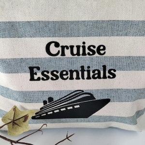 May include: A white and blue striped canvas zippered pouch with the text "Cruise Essentials" and a black silhouette of a cruise ship.