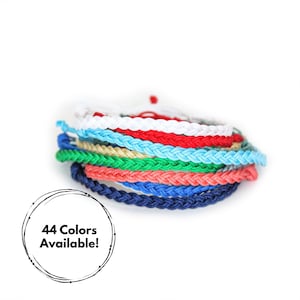 May include: A stack of 8 colorful braided bracelets in white, red, blue, green, beige, and coral. 44 Colors Available! is written in a circle.