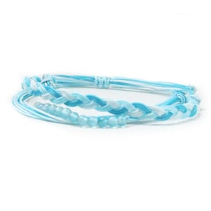 May include: A set of three blue and white friendship bracelets with blue glass beads.