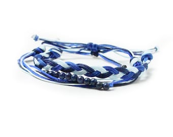 Puede incluir: Un brazalete trenzado con cuerda azul y blanca y cuentas azul oscuro.