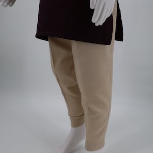 May include: A maroon long-sleeved shirt with a side slit and beige pants.