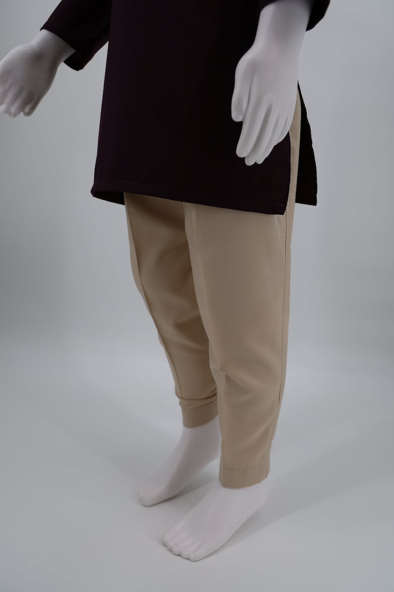 May include: A maroon long-sleeved shirt with a side slit and beige pants.