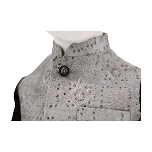 May include: A gray vest with a silver button and intricate embroidery. The vest has a mandarin collar and a black lining.