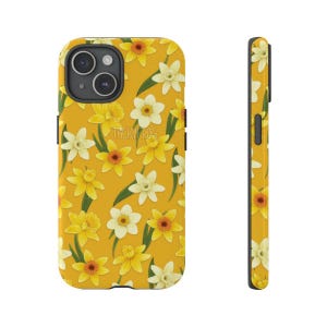 May include: Yellow phone case with a floral pattern of yellow and white daffodils. The case has a black camera lens and the text "TACKYFROG" is visible. The case is shown from the front and side.