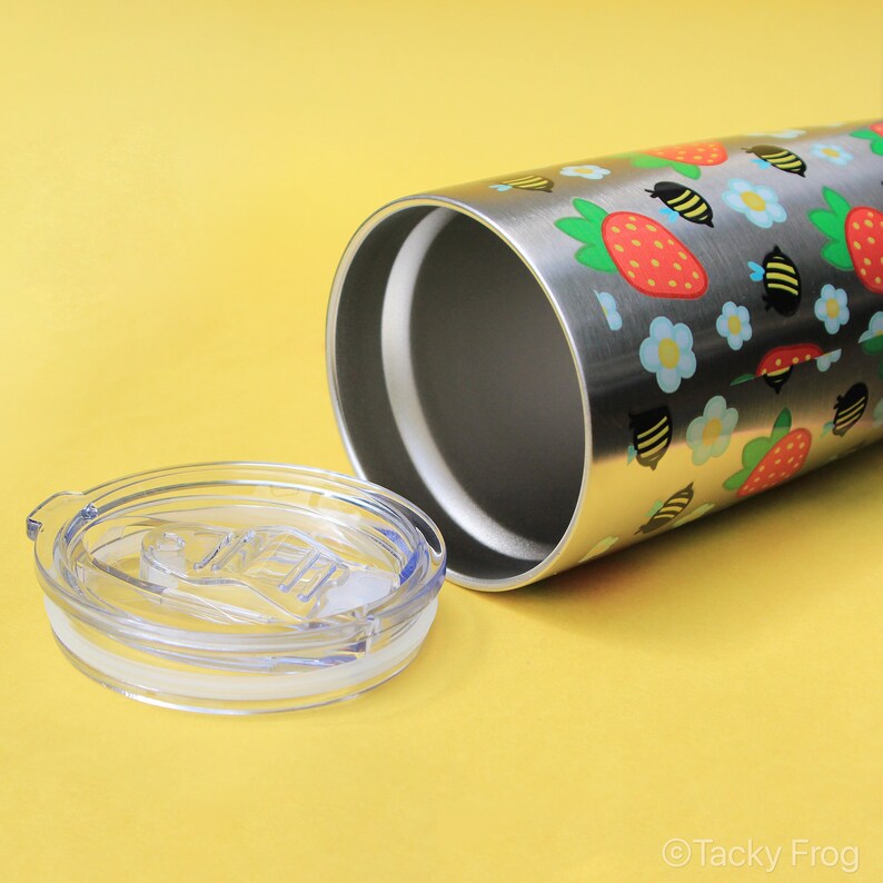 Puede incluir: Vaso de acero inoxidable con tapa transparente. El vaso est&aacute; decorado con un estampado de fresas, abejas y flores azules. La tapa es transparente con una junta blanca.