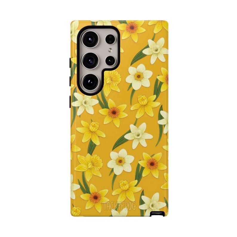 May include: A yellow phone case featuring a pattern of yellow and white daffodils with green leaves. The case has a camera cutout and the text "TACKYPEDOG" at the bottom. The case is designed for a smartphone.
