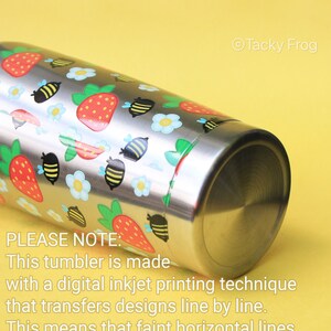 Puede incluir: Vaso de acero inoxidable con un colorido dise&ntilde;o de fresas, abejas y flores. El texto "Tacky Frog" es visible. El vaso est&aacute; hecho con una t&eacute;cnica de impresi&oacute;n digital de inyecci&oacute;n de tinta. Pueden ser visibles l&iacute;neas horizontales.