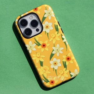 May include: Yellow phone case with a floral daffodil pattern. The case features a repeating design of yellow and white daffodils with green leaves. The brand name "TACKYFROG" is printed at the bottom.