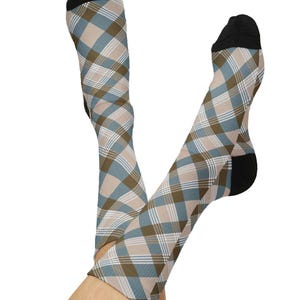 Puede incluir: Un par de calcetines hasta la rodilla con un diseño de cuadros en tonos azules, marrones y beige. Los calcetines tienen punteras y talones negros. Los calcetines son estampados.