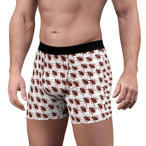 May include: Boxer briefs featuring a repeating pattern of brown cockroaches on a white background. The garment has a solid black elastic waistband and visible black stitching along the front panel seams, providing a secure and fitted appearance.