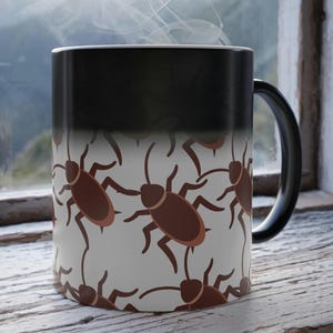 May include: A black and white color-changing coffee mug with a repeating pattern of brown cartoon cockroaches. The mug has a black handle and is filled with a hot beverage, as indicated by the rising steam.