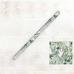 Könnte beinhalten: Ein weißer Apple Pencil mit einem grün-weißen Blumenmuster. Das Muster zeigt Blätter, Blumen und Ranken.