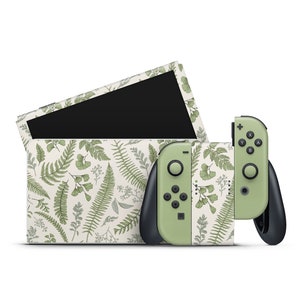 Könnte beinhalten: Eine grüne und weiße Nintendo Switch Konsole und ein Controller mit einem Farnmuster. Die Konsole ist geschlossen und der Controller ist abgenommen.
