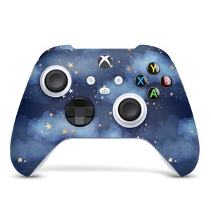 May include: A blue and white Xbox controller with a starry night sky design. The controller has gold accents and a white faceplate.