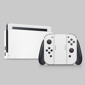 以下が含まれることがあります： 白いニンテンドースイッチ本体と、白いJoy-Conコントローラーが接続されています。本体は閉じられており、コントローラーには黒いボタンと赤いボタンがあります。