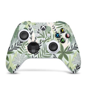 Könnte beinhalten: Ein weißer Xbox-Controller mit einem grün-weißen Blumenmuster. Der Controller hat die Standard-Xbox-Tasten: A, B, X, Y und ein Steuerkreuz.