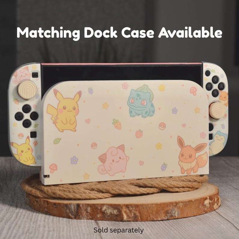 May include: A gaming console dock and controller set featuring a cream-colored skin with pastel illustrations of Pikachu, Bulbasaur, Clefairy, and Eevee, along with small flowers and berries. The text Matching Dock Case Available and Sold separately appears.