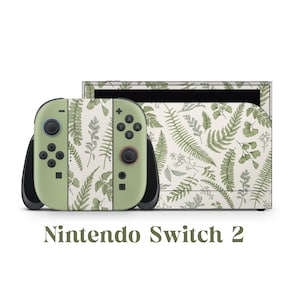 Puede incluir: Una consola Nintendo Switch 2 con una piel personalizada con un patrón botánico de helechos y hojas en tonos verdes y blancos. Los mandos son de color verde claro con detalles y botones negros. El texto "Nintendo Switch 2" se muestra debajo.