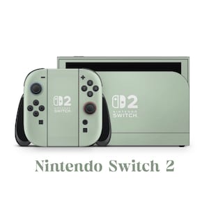 May include: A mint green Nintendo Switch 2 console with matching controllers. The controllers have black accents and buttons. The console and controllers have the Nintendo Switch logo. The text "Nintendo Switch 2" is below the console.
