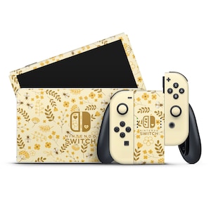 Op de afbeelding: Een gele en bruine Nintendo Switch-console en twee bijpassende Joy-Con-controllers met een bloemenpatroon en de tekst "Nin' the N.D.O. Switch" en "Nintendo Switch".