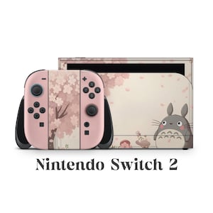以下が含まれることがあります： カスタムデザインのNintendo Switch 2コンソール。Joy-Consは桜のデザインでピンク色です。コンソールの背面には漫画のキャラクターと桜のアクセントがあります。「Nintendo Switch 2」の文字が下にあります。