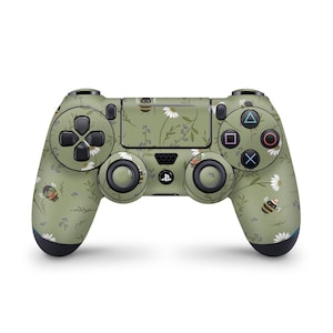 May include: A green and black PlayStation 4 controller with a floral and bee design. The controller has a green background with white daisies, green leaves, and small bees.