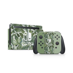 Może przedstawiać: Zielona konsola Nintendo Switch i kontroler z tropikalnym wzorem liści. Konsola ma nadrukowany napis "Nintendo Switch".
