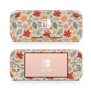 May include: A beige Nintendo Switch Lite console with a colorful autumn leaf pattern. The console has a pink screen and the Nintendo Switch logo is visible on the front.