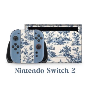 May include: A Nintendo Switch 2 console with a blue and white toile pattern. The controllers are light blue with black accents and buttons. The console and controllers feature a classic landscape design in blue on a cream background. The text "Nintendo Switch 2" is below the console.
