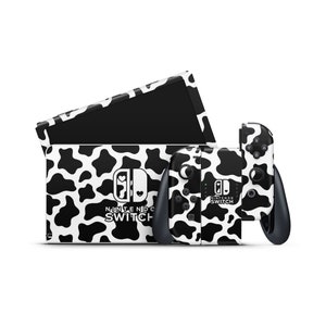 Può includere: Una pelle per console Nintendo Switch e due controller con un motivo a mucca bianco e nero. La pelle della console ha il logo Nintendo Switch e il testo "Nintendo Switch".