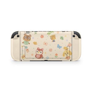Pu&ograve; includere: Una console Nintendo Switch color crema con un design colorato con personaggi dei cartoni animati, tra cui Tom Nook e Isabelle. Il design include farfalle, fiori e frutta. La console ha dettagli neri sui lati.