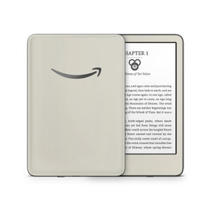 May include: A white e-reader with a black border and a black screen displaying the text "CHAPTER 1" and "Flame of Tar Valon". The screen also shows a symbol with three circles and a small Amazon logo on the front of the e-reader.