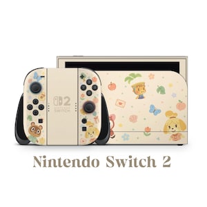 May include: Cream-colored Nintendo Switch 2 console with a matching dock. The Joy-Con controllers and dock feature a whimsical design with cartoon characters, butterflies, and floral accents. The text "Nintendo Switch 2" is displayed below the console.