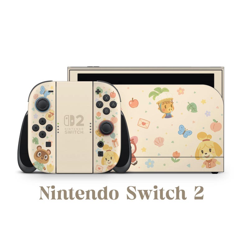Pu&ograve; includere: Console Nintendo Switch 2 color crema con dock abbinato. I controller Joy-Con e il dock presentano un design stravagante con personaggi dei cartoni animati, farfalle e accenti floreali. Il testo "Nintendo Switch 2" &egrave; visualizzato sotto.