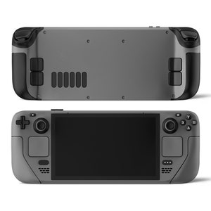 May include: A gray handheld gaming console with a black screen, buttons, and joysticks. The console has a textured surface and a sleek design.