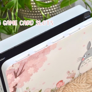 May include: A white and pink game card case with a Totoro character design. The case has 5 game card slots and the text "5 GAME CARD SLOTS" is printed on the top.