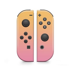 Puede incluir: Un par de mandos Joy-Con de Nintendo Switch de color rosa y amarillo. El Joy-Con izquierdo tiene una cruz direccional y cuatro botones. El Joy-Con derecho tiene cuatro botones de acción, una palanca de mando y un botón de inicio.