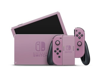 Puede incluir: Una consola Nintendo Switch rosa con un mando Joy-Con rosa. La consola tiene un logotipo de Nintendo Switch rosa y blanco con un diseño de corazón. El mando Joy-Con tiene un logotipo de Nintendo Switch rosa y blanco con un diseño de corazón.