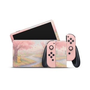 以下が含まれることがあります： ピンク色の桜のデザインが施された、Nintendo Switchのコンソールとコントローラー。ピカチュウとミュウのイラスト、川と木の風景が描かれています。コントローラーはピンク色で、黒色のアクセントが付いています。