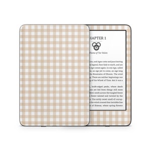 Könnte beinhalten: Ein Kindle E-Reader mit einer weißen und beigefarbenen Gingham-Musterhülle. Der Bildschirm zeigt den Text "CHAPTER 1" und "Flame of Tar Valon".