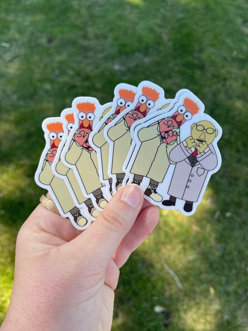 May include: A set of six stickers featuring a red-haired character in a white lab coat with a surprised expression. The character is holding a smaller character with a mustache and glasses in a lab coat. The stickers are printed on white paper.