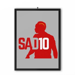 May include: A red silhouette of a soccer player with the number 10 and the word "SAD" in white letters on a gray background.