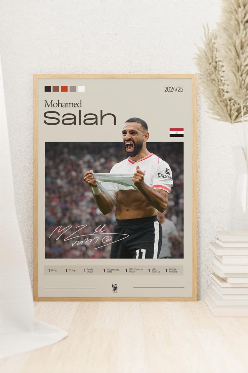 Op de afbeelding: Een poster met een foto van Mohamed Salah, een professionele voetballer, die een doelpunt viert. De poster is beige met zwarte tekst en een rode en witte voetbalafbeelding. De tekst op de poster luidt "Mohamed Salah" en "2024/25".