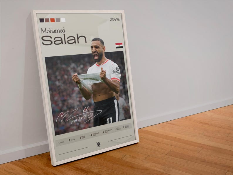 Op de afbeelding: Een witte geframed poster met een foto van Mohamed Salah die een doelpunt viert. De poster heeft een witte achtergrond met zwarte tekst die "Mohamed Salah" en "2024/25" zegt. De poster heeft ook een kleine Egyptische vlag in de rechterbovenhoek.